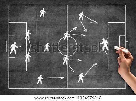 Businessman hand with chalk draws scheme of game. Freehand illustration on blackboard. Planning strategy and tactics of next game. Soccer field with players pictograms. Team game competition concept