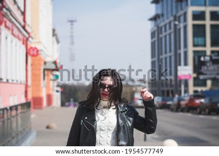 beautiful hipster girl in the spring walks along the street of her city on a warm sunny day