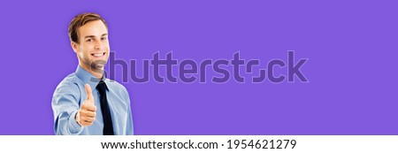 Portrait of smiling confident businessman showing thumbs up like hand sign gesture, over violet purple color background. Happy confident man gesturing. Copy space area. Success in business ad concept 
