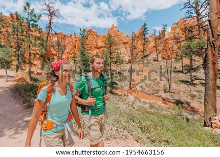 Hiking couple hikers walking smiling happy in summer mountain nature. Interracial couple Asian woman and Caucasian man in Bryce Canyon National Park landscape, Utah, United States. Royalty-Free Stock Photo #1954663156