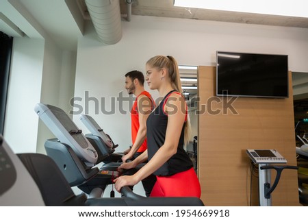 Couple working out at a gym, running on a treadmill