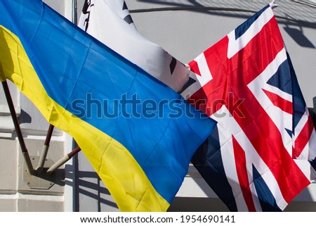 Ukrainian and United Kingdom flags waving on the wall of house Royalty-Free Stock Photo #1954690141