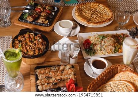 Family feast of Desi barbecue dinner with Kebab and Naan with sauces, Buffet and Drinks Served on a table  Royalty-Free Stock Photo #1954715851