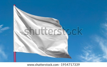 Clean blank white flag on flagpole against blue sky, as background for text