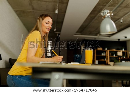 Young woman recording podcast using microphone. Radio host working from home office.