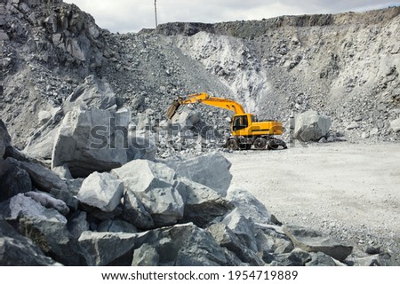 Quarry excavator hydraulic hammer crushes large stones in a limestone quarry. Royalty-Free Stock Photo #1954719889