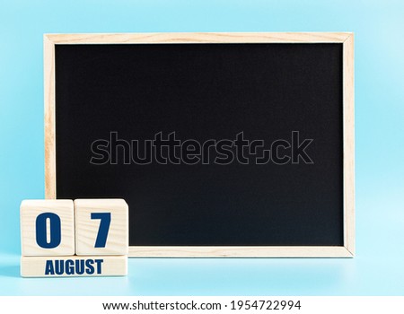August 7th. Day 7 of month, Cube calendar with date, empty frame on light blue background. Place for your text. Summer month, day of the year concept