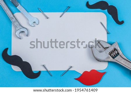Wrenches, nails and a callout for text lie in the middle on a light blue background, a close-up top view.