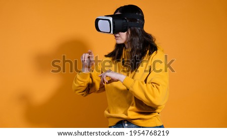 young woman with a virtual reality device on a yellow background.