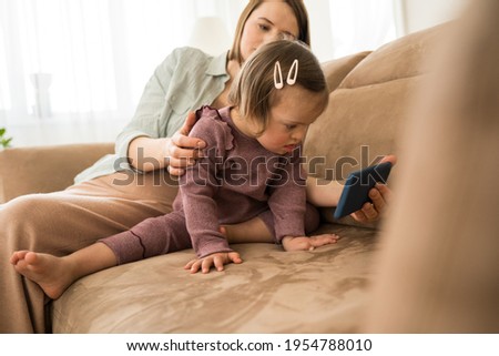 Woman showing cartoons at the smartphone to her little daughter