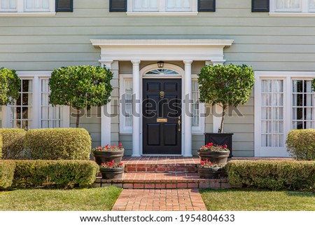 Front door of classic home with landscaped front yard and brick path. Royalty-Free Stock Photo #1954804633