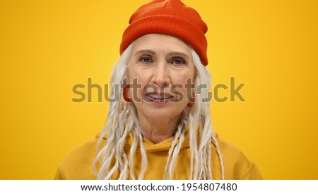 Aged happy woman having fun inside. Portrait of cheerful senior lady opening mouth on yellow studio background. Smiling old female person dancing indoors. Royalty-Free Stock Photo #1954807480