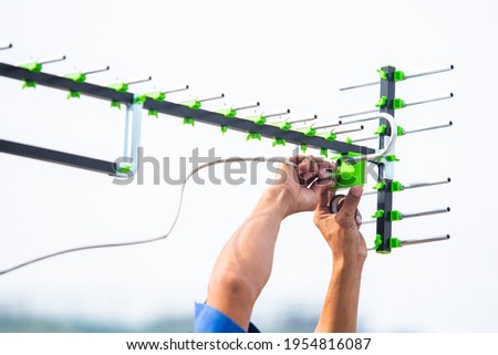 Selective focus to The digital TV antenna with the hands of a technician is installing. Royalty-Free Stock Photo #1954816087