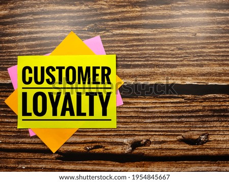 Customer loyalty, the phrase is written on multi-colored stickers, on a brown wooden background. Business concept, strategy, plan, planning.