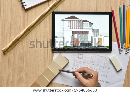 a tablet showing architectural drawing design detail selection of building color with digital pens on wood table, the concept of new technology for working of tablet with digital pen