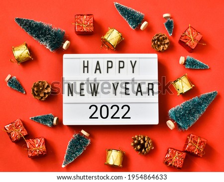 Light box with text HAPPY NEW YEAR 2022 and New Year decorations on a red background. Holiday concept. Flat lay. View from above. Postcard.