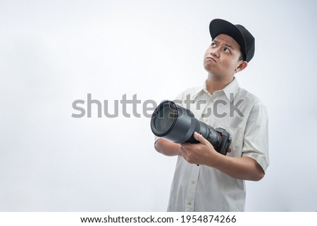 The photographer pose with holding the professional camera and tele lense isolated in white background.
