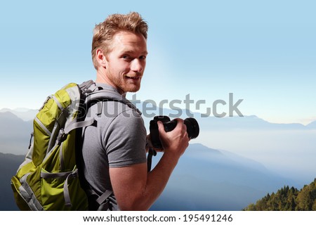 Young man with backpack taking a photo on the top of mountains, caucasian