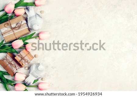 Festive border with tulip flowers, gifts and birds on light marble. Frame top down composition with copy space. Valentine's Day, Mother's Day or 8 March greeting card.