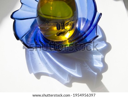 olive oil bottle on a blue dish with reflections showing through. product photography
