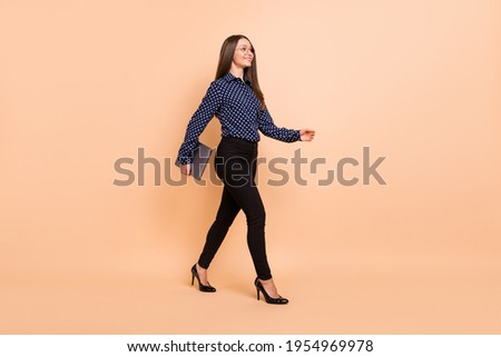 Photo of pretty shiny young girl dressed dotted blouse glasses holding modern device walking isolated beige color background
