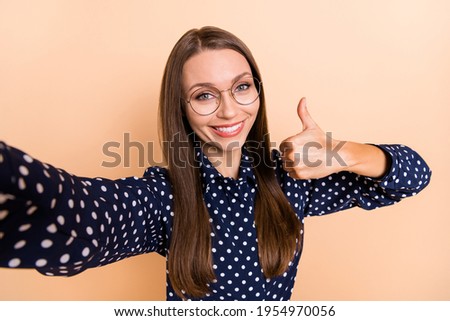 Photo of young woman happy positive smile show thumb-up like cool make selfie isolated over beige color background