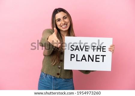 Young caucasian woman isolated on pink background holding a placard with text Save the Planet making a deal