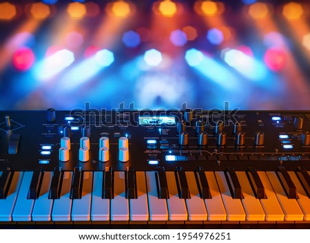 Musical instrument electronic synthesizer on a background of colored rays. Background on the theme of music, disco and synthesizer games.