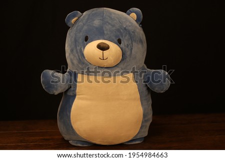 Happy blue bear standing in a spotlight