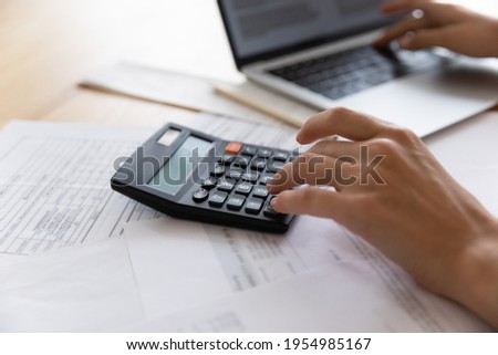 Auditor workplace. Close up of woman professional bookkeeper at work counting expenses costs planning savings economy making payment. Focus on female accountant hand pressing electronic calculator key Royalty-Free Stock Photo #1954985167