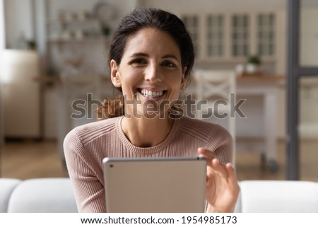 Easy online learning. Headshot portrait of motivated latin woman study in internet from home sit on cozy sofa hold digital pad look at camera above screen. Happy young lady relax using modern tablet