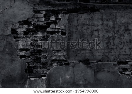 Old gloomy brick wall with peeling plaster and cracks. Dark night illumination of a graveyard stone fence. Grunge background