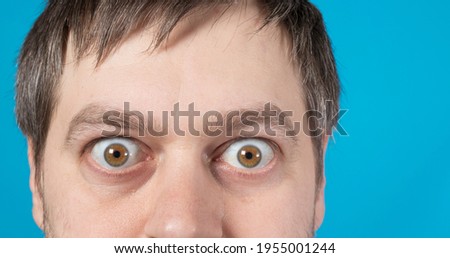 Surprised eyes of a man on a blue background with room for text to copy space. Big bulging eyes. To advertise discounts, sales, pawnshops or credit. Royalty-Free Stock Photo #1955001244