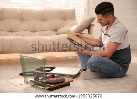 Man with vinyl record near turntable in living room