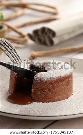 White Plate of delicious fresh fondant with hot chocolate inside on white wood background 