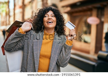 Young hispanic woman shopping holding credit card at the city.