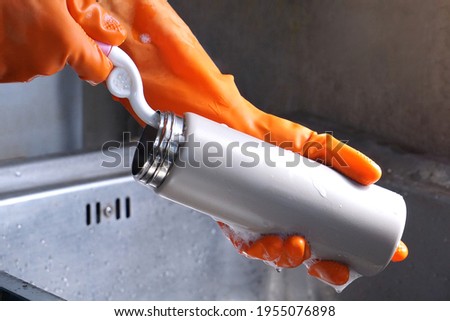 A young woman's hand was holding a sponge brush to clean the Drinking water bottle. The concept of cleaning containers used in everyday life. Royalty-Free Stock Photo #1955076898