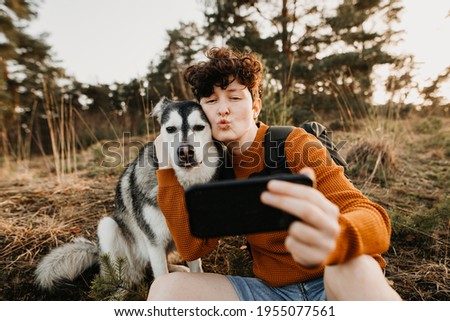 Young woman and dog taking duck face selfie 