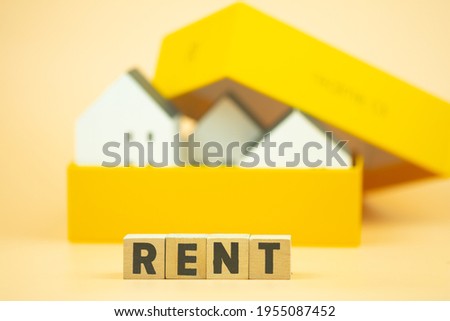 RENT text on wooden cubes with miniature home in box. The concept of rent home