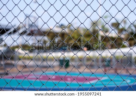  A  basketball field with fence,A mesh is a barrier made of connected strands of metal, fiber, or other flexible or ductile materials.  similar to a web or a net ,it has many attached or woven strands