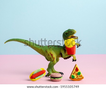 Close up dinosaur with fast food. Creative still life unhealthy lifestyle.