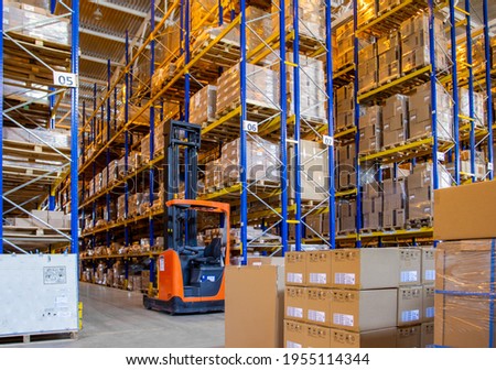 Interior of a modern warehouse storage with rows and goods boxes on high shelves. Pallet truck parking near shelves Royalty-Free Stock Photo #1955114344