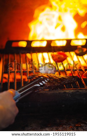 Cooking meat and 2d on fire. Grill and barbecue. Chef cats steak in the restaurant. Close-up.
