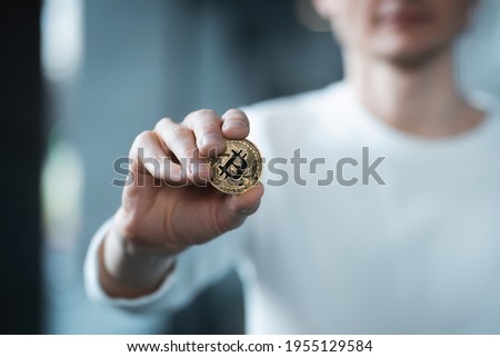 closeup of male investor holding golden bitcoin or cryptocurrency in hand