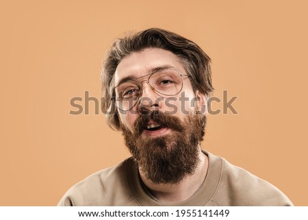 Half-length portrait of Caucasian serious man in glasses isolated over light yellow background. Mustache and beard. Concept of human emotions, facial expression, sales, ad, fashion. Copy space for ad.