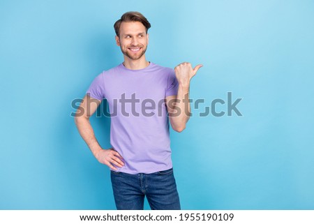 Photo portrait of curious guy pointing thumb on copyspace isolated on pastel blue color background