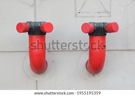 Two fire hydrant nozzles are attached to the building wall.