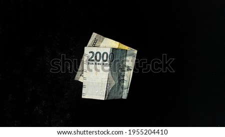 2000 rupiah banknotes from Indonesia on a black background
