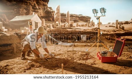 Archaeological Digging Site: Great Female Archeologist Work on Excavation Site, Cleaning Cultural Artifacts with Brush and Tools. Discovery of Ancient Civilization Temple, Architecture, Fossil Remains Royalty-Free Stock Photo #1955213164