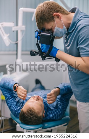 The orthodontist takes a picture of the teeth with a camera. A man at the dentist's office.